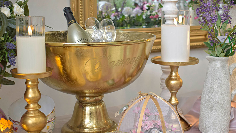 large golden champagne bowl, golden candlesticks with candles on tea party table