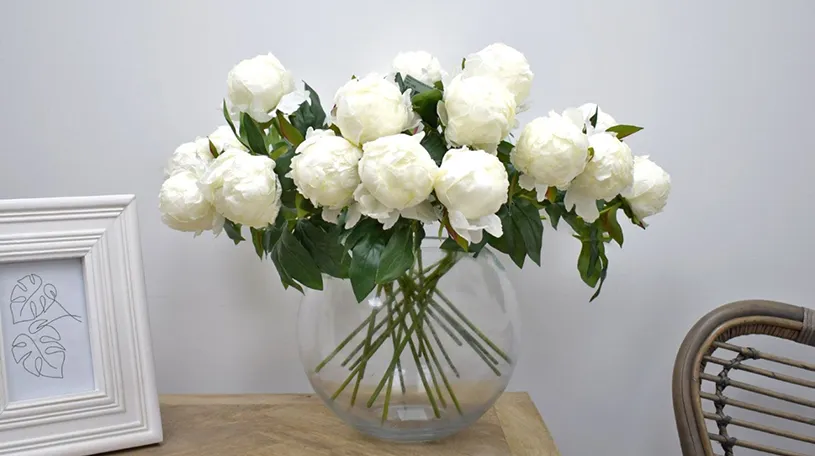 white faux flowers in fish bowl glass vase