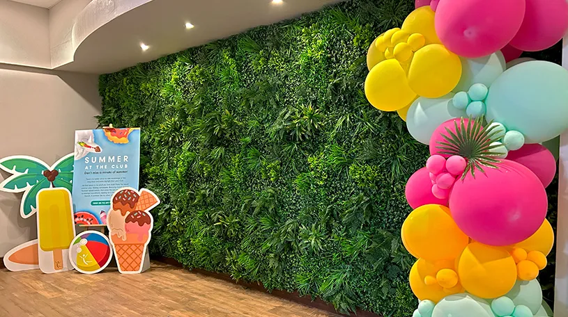 artificial green wall installed at a health club with signs and balloons