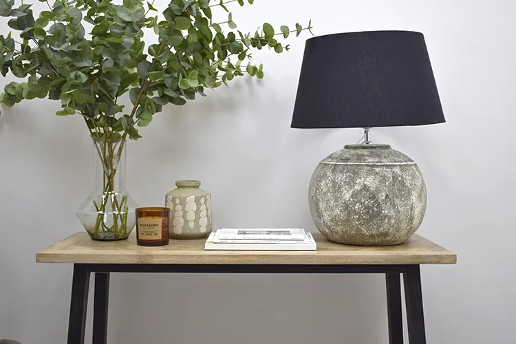 styling a console table with faux foliage, vase, candles, and lamp